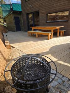 a grill in front of a bench and a picnic table at Hillside Cabin in Pomezí