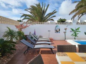 a row of chairs on a patio with a pool at Villa Acoran in Costa Teguise
