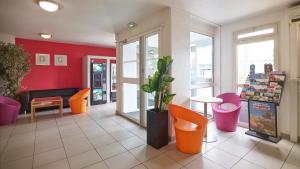 a waiting area of a store with orange and pink chairs at Première Classe Rosny Sous Bois in Rosny-sous-Bois
