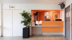 an office lobby with an orange counter and a potted plant at Première Classe Rosny Sous Bois in Rosny-sous-Bois