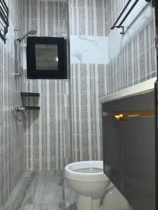 a bathroom with a toilet and a tv on the wall at La MAISON SEONE SILVER in Abidjan +2 photos