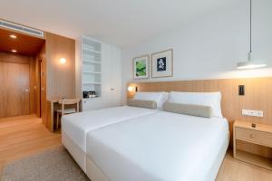 ein Schlafzimmer mit einem großen weißen Bett und einem Schreibtisch in der Unterkunft Hotel Orquidea in Funchal + 16 Fotos