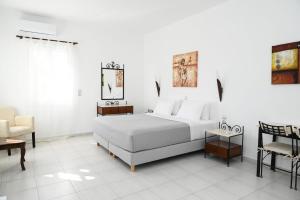 a white bedroom with a bed and a chair at Asterias Boutique Hotel in Pachaina