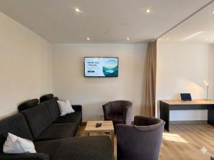 a living room with a couch and a tv on the wall at W-Apartments - Spacious Parking, EV-Station, Washer & Private Garden in Offenburg