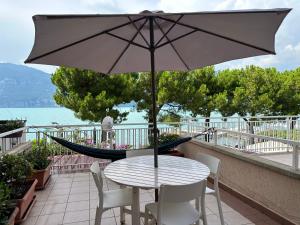 a table and chairs with an umbrella on a balcony at Lake Apartment by GardaDoma in Brenzone sul Garda