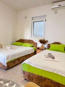 two beds in a room with green pillows at Apartmani Vista Čanj in Čanj