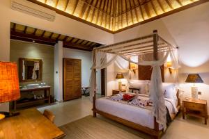 a bedroom with a canopy bed and a desk at Ulun Ubud Resort - CHSE Certified in Ubud