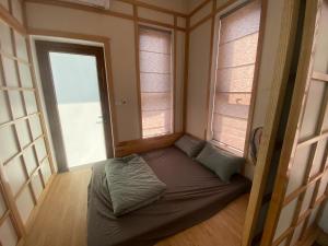 a small bed in a room with two windows at Lexe Palace Tam Dao in Tam Ðảo