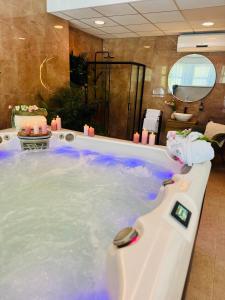 a jacuzzi tub with blue water in a bathroom at Plaza Hotel Gyula in Gyula +73 photos