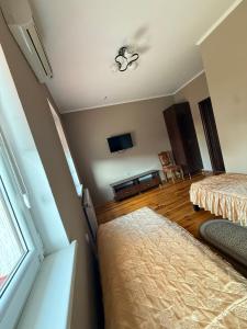 a bedroom with two beds and a flat screen tv at Troyanda in Radyvyliv