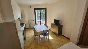 a kitchen with a dining room table and a kitchen with a television at Familiar apartment with terrace in Rosolina in Rosolina Mare
