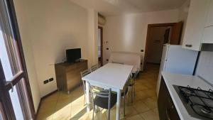 a kitchen with a white table and a refrigerator at Familiar apartment with terrace in Rosolina in Rosolina Mare +15 photos