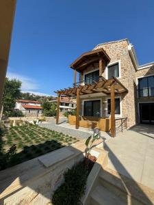 a house with a wooden pergola in the yard at Ultava Koru Suites in Datca