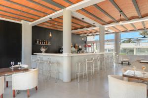 a restaurant with a bar with stools and tables at Vibra Caleta Playa Apartmentos-3SUP in Sa Caleta