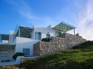 a white house on a hill with a stone wall at Asterias Boutique Hotel in Pachaina