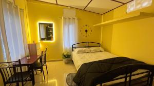 a yellow bedroom with a bed and a table and chairs at Niroda homestay in Jorhat