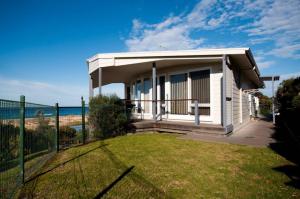 a small house on the beach with a fence at Pelicans Perch in Lake Tyers