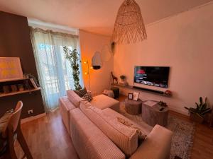 a living room with a couch and a flat screen tv at T2 cosy - proche centre et plage in Quiberon