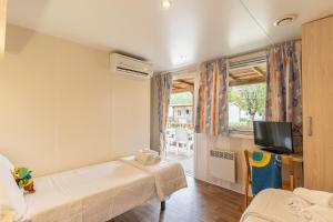 a small room with two beds and a tv at Club del Sole Marina Family Resort in Punta Marina