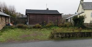 a wooden building in a yard next to a house at Gîte de Brocéliande in Saint-Malo-de-Beignon