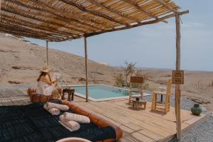 a woman sitting on a deck next to a swimming pool at Mia Agafay Resort in El Karia