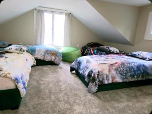 a attic bedroom with three beds and a window at Cookie's Cottage in Caseville