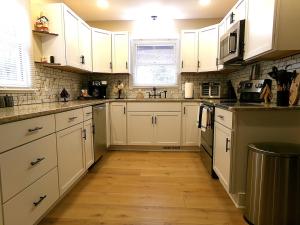 a kitchen with white cabinets and a wooden floor at Cookie's Cottage in Caseville