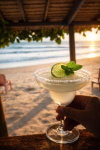 a person holding a drink with a lime on the beach at The Dreamcatcher Hostel Nathon SamuiSunset in Nathon