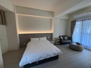 a bedroom with a large bed and a chair at 星爍民宿 in Ch'ih-k'an-lou