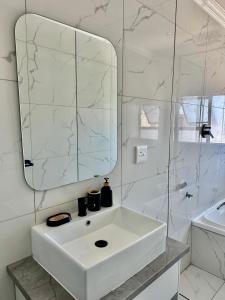 ein weißes Badezimmer mit Waschbecken und Spiegel in der Unterkunft Cingar Suites in East London + 12 Fotos