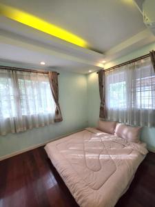 a large bed in a room with two windows at Sugar Beach Villa Bangsaen in Ban Bang Saen (1)