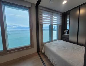 a bedroom with a bed and two large windows at Busan#Gwanganli#Hot place#Healing Home in Busan