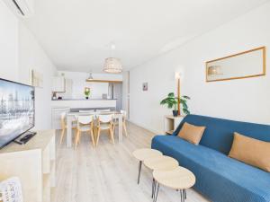 a living room with a blue couch and a dining room at Résidence de Tourisme l'Albatros in Palavas-les-Flots
