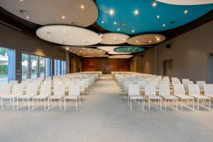 a conference room with white chairs and a blue ceiling at Hotel SB BCN Events 4* Sup in Castelldefels