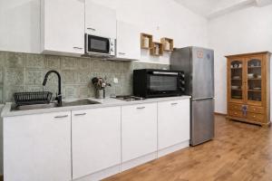 a kitchen with white cabinets and a stainless steel refrigerator at Natururlaub Eifel-Mandala Feriewohnung in Kall