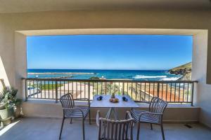 a balcony with a table and chairs and the beach at Solmare beachfront apartments in Panormos Rethymno