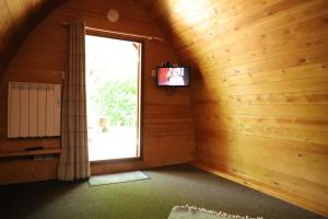an attic room with a window and a television at Camping Pod's in Hanworth