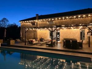 a pergola with lights next to a swimming pool at Le Jardin d'Elusa in Eauze