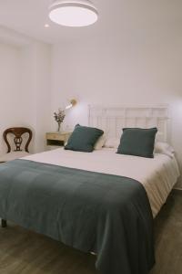 a bedroom with a large white bed with green pillows at Casa Aula Minerva Sapientia 2 Habitaciones in Almedinilla