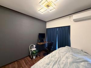 a bedroom with a bed and a desk with a computer at 民泊 みづき 一棟貸し in Ibusuki