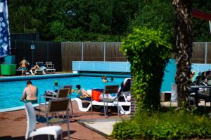 a pool with people sitting in chairs and people swimming at CampingHotel Renesse in Renesse