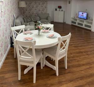 a white dining room table with four chairs and a white table at Dare apartments 2 in Giurgiu