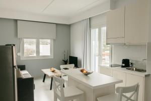 a white kitchen with a table and chairs and a counter at Meltemi Beach Apartments 2 in Milatos