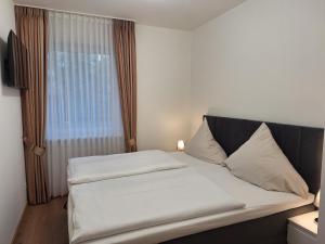 a bedroom with a bed with white sheets and a window at Ferienhof Große Drieling in Greven