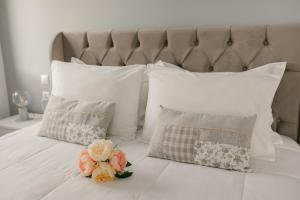 a white bed with white pillows and flowers on it at Meltemi Beach Apartments 2 in Milatos