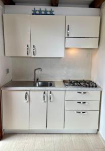 a kitchen with white cabinets and a sink at Punta Est - Mono TRAMONTANA Soppalco & Sea View in Capo Coda Cavallo