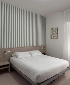 a bedroom with a large bed with white sheets at Hotel Ammare in Sottomarina