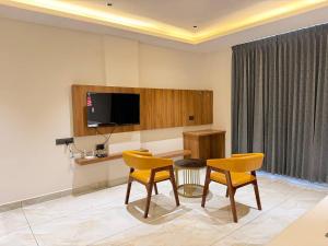 a room with a table and two chairs and a television at Hotel Grand Central Mysore in Mysore