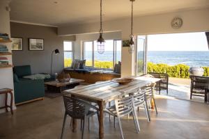 a dining room with a table and chairs and the ocean at Seafront house with a view in Kleinmond