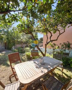 a wooden picnic table and two chairs under a tree at Sardegna 20 in San Teodoro